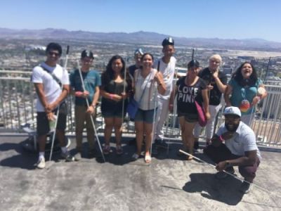 Tarik Williams crouches down in front of a group of his students during an outing at the NFB National Convention in Las Vegas.