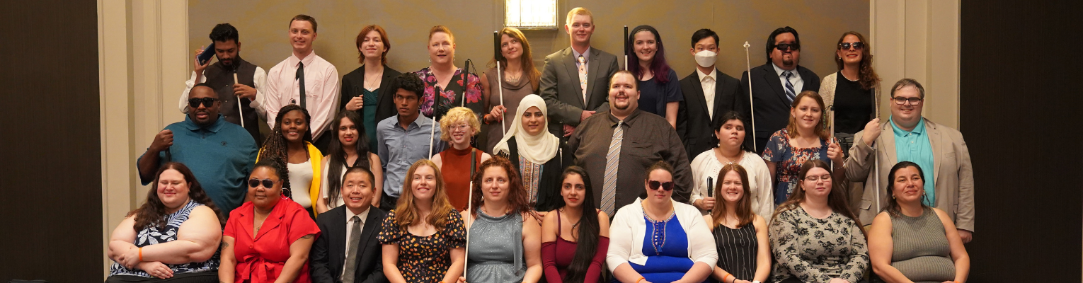 Scholarship Class Photo of 30 diverse blind students in three rows, Colin is in the first row on the left
