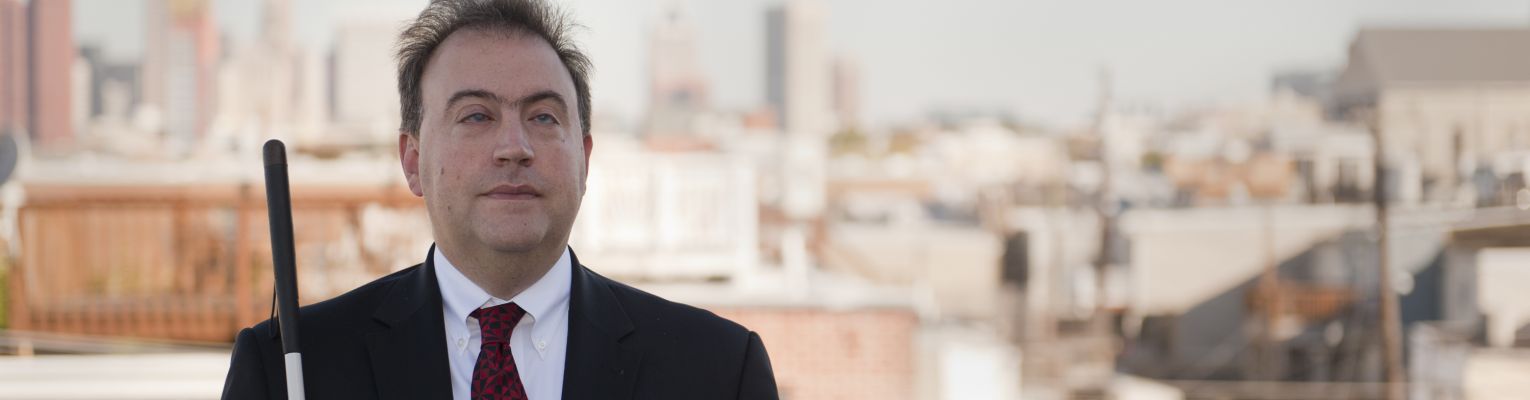 President Riccobono stands on balcony with city of Baltimore in the background