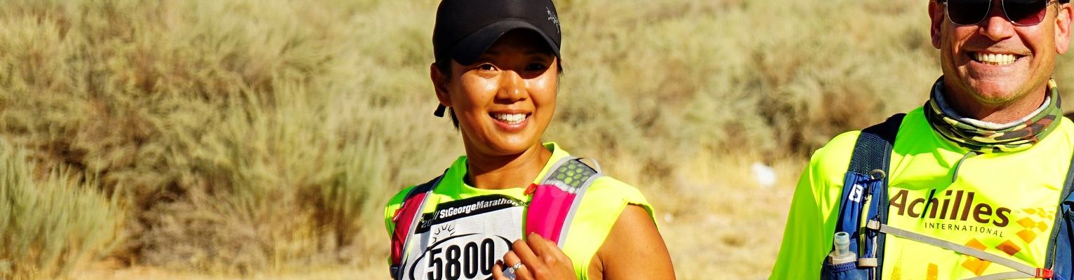 Terri Rupp smiles as she runs a race outside next to her guide.