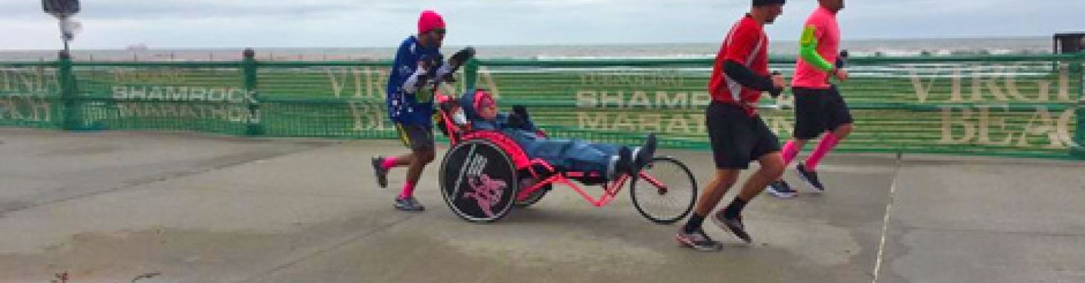 Michael pushes his friend Ashton in the Boston Marathon. Two other members of Team Hoyt run with them.