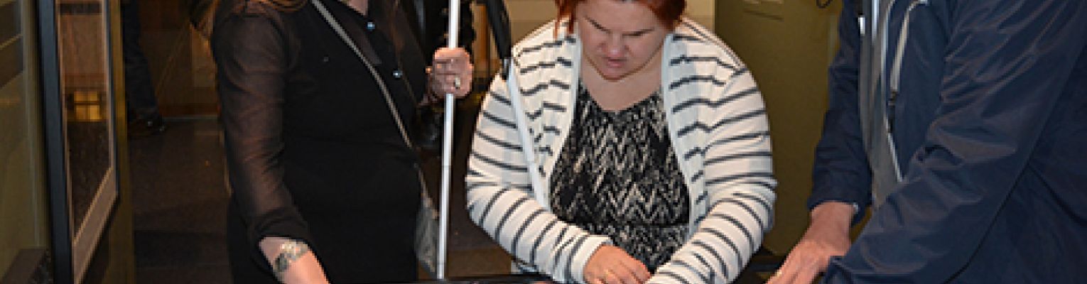 Blind museum goers interact with one of John Olsen's tactile photographs. 