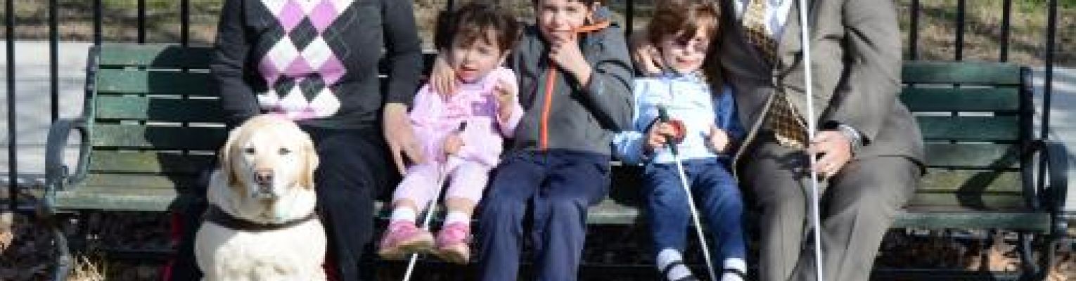 The Riccobono family sits on a park bench smiling.