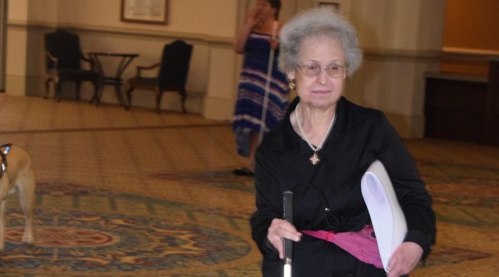 A woman with a white cane walks to a session at the NFB National Convention.