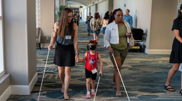 An orientation and mobility instructor teaches a blind child wearing sleepshades cane travel.